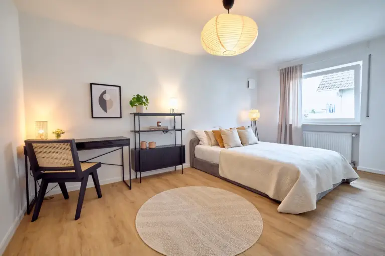 Spacious second bedroom at CORAL BLOOM with queen-size bed, dedicated workspace, shelving and warm ambient lighting