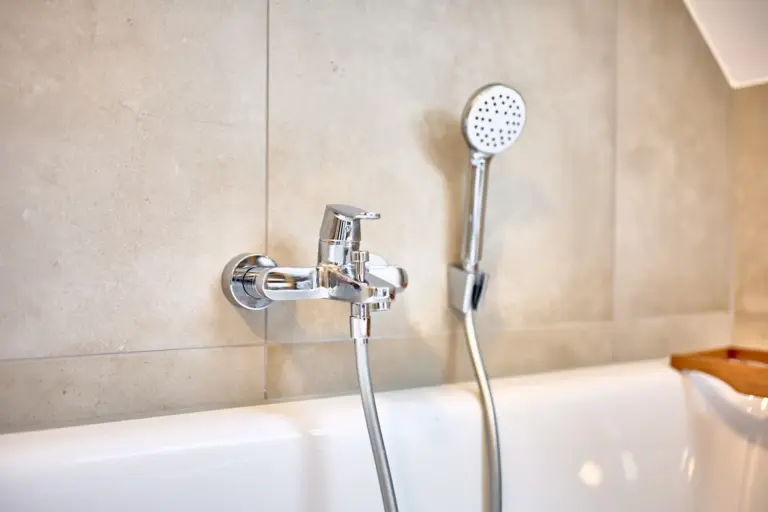 Close-up of chrome bathtub faucet and handheld shower in the bathroom at CORAL SUN