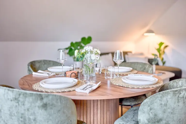 Elegant dining area with a round wooden table and green upholstered chairs in CORAL SUN