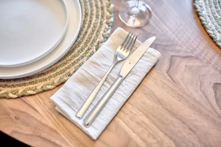 Elegant table setting with white plates, linen napkin and silverware in the CORAL SUN dining area