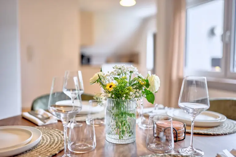 Close-up of the elegantly set dining table with fresh flowers, tableware and wine glasses in CORAL SUN