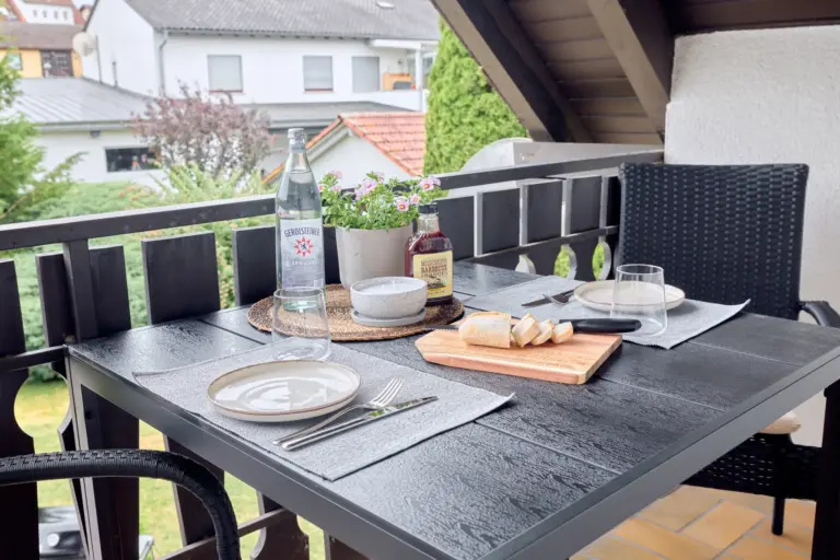 Covered balcony at CORAL SUN with outdoor dining table, two chairs and views of the surrounding greenery