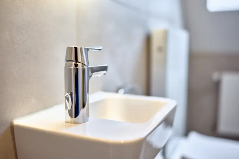 Close-up of a modern chrome faucet and white washbasin in the half bath at CORAL SUN