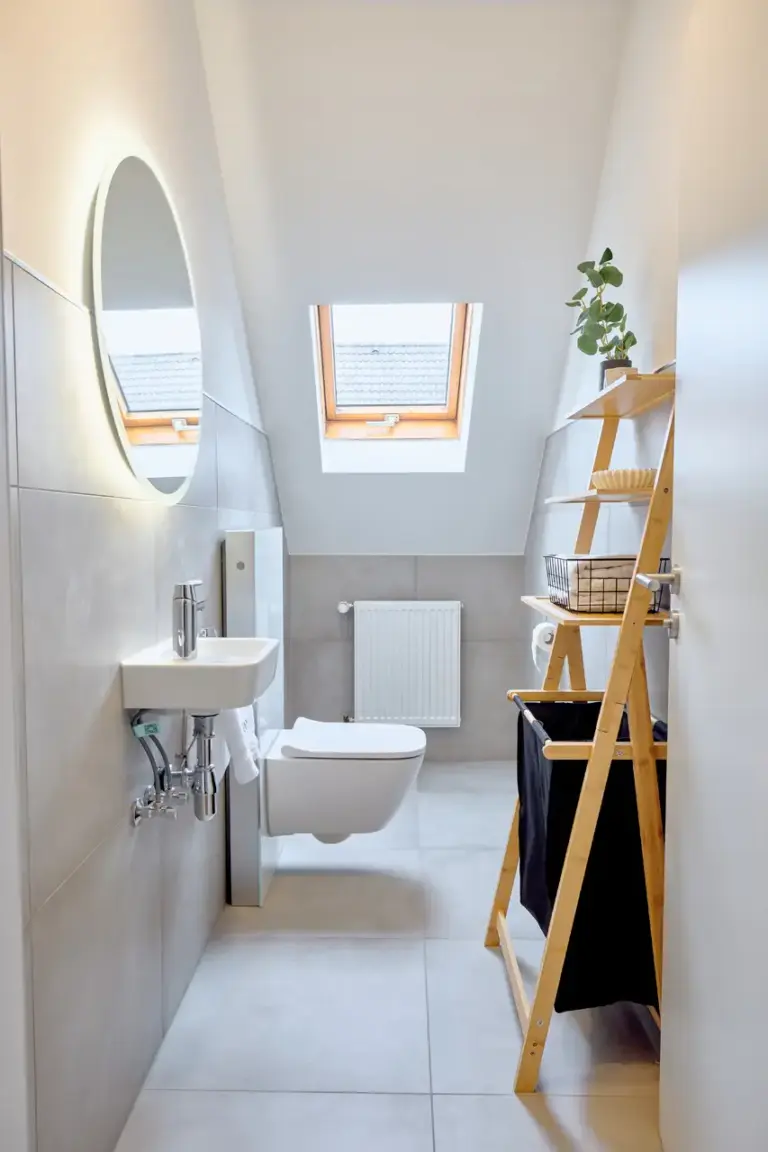 Bright CORAL SUN half bath with wall-mounted toilet, compact sink, illuminated mirror and skylight