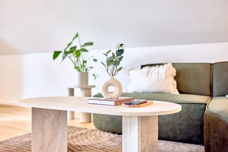 Modern coffee table with decorative vase, books and greenery in front of the green sofa at CORAL SUN