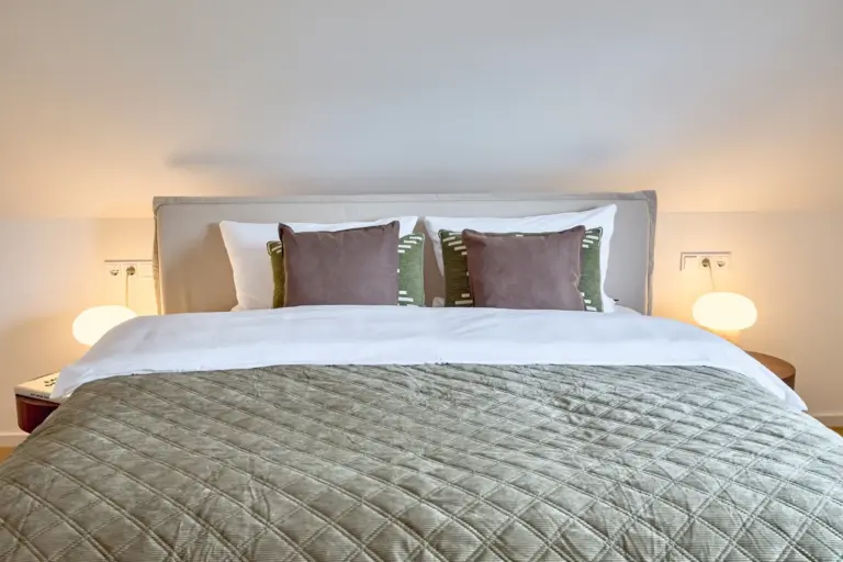 CORAL SUN master bedroom bed with white bedding, green quilt and layered cushions