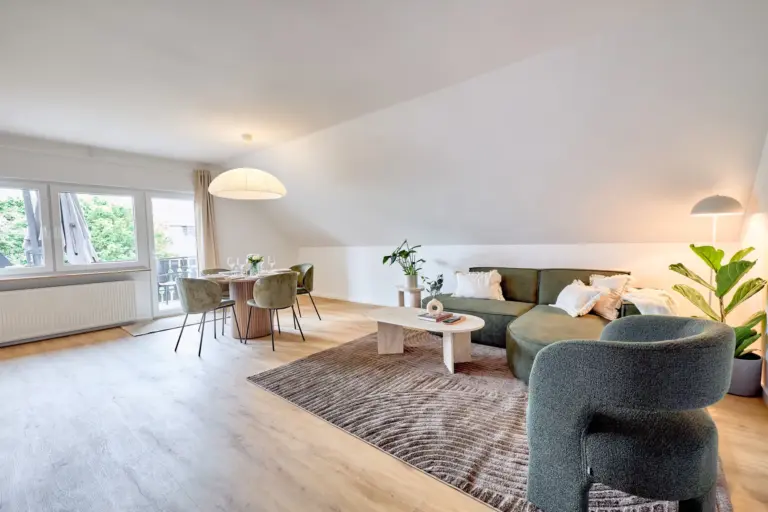 Spacious open-plan living and dining area in CORAL SUN with green corner sofa, armchair and dining table for four