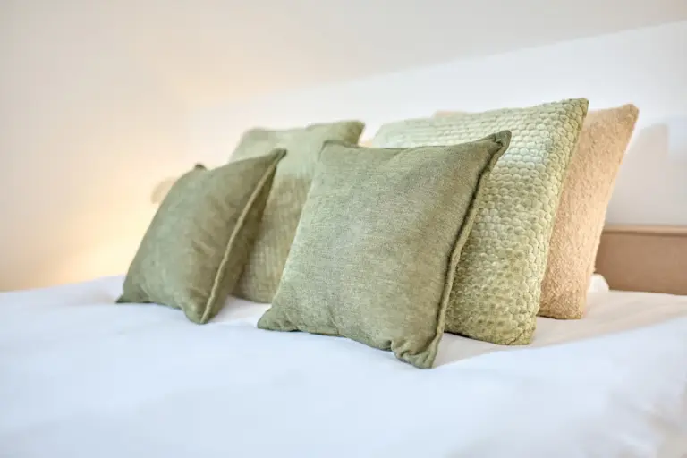Close-up of layered green and beige decorative pillows in CORAL SUN’s second bedroom