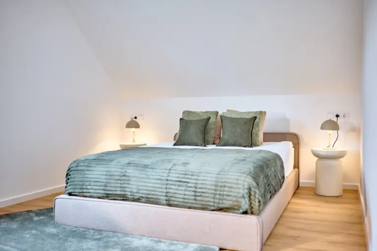 Second bedroom with queen-size bed, green textiles and bedside lamps at CORAL SUN