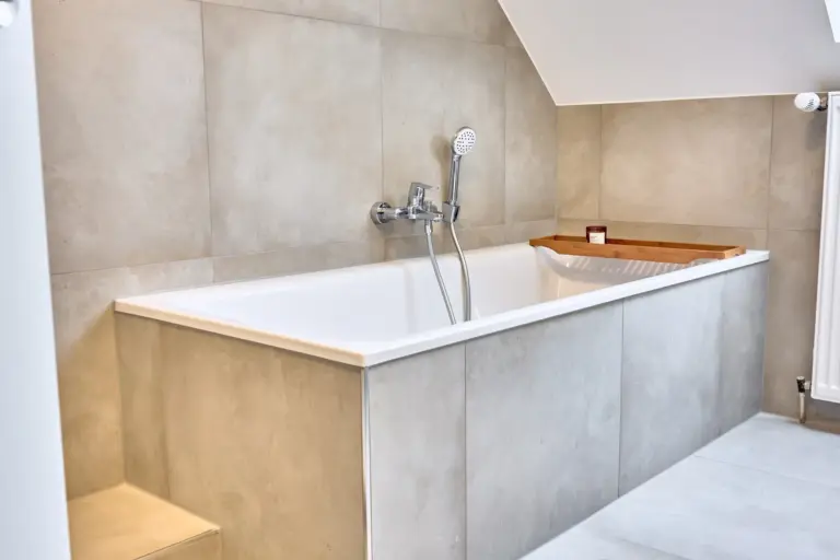 Modern bathtub with handheld shower and wooden bath tray in the bathroom at CORAL SUN