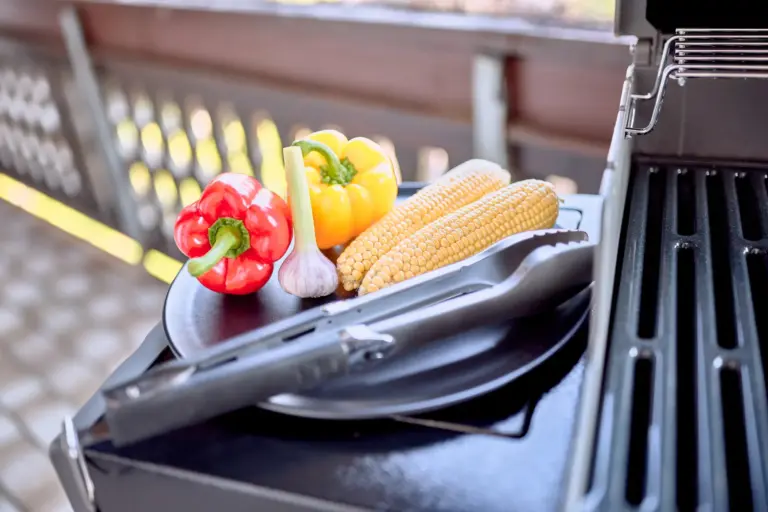 Gas grill with vegetables and barbecue utensils on the balcony at RUBY NOIR
