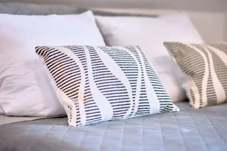 Bedding and decorative pillows on the king-size bed at RUBY NOIR