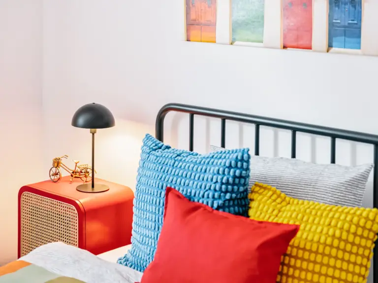 Queen-size bed with colorful pillows at PEARL WHITE